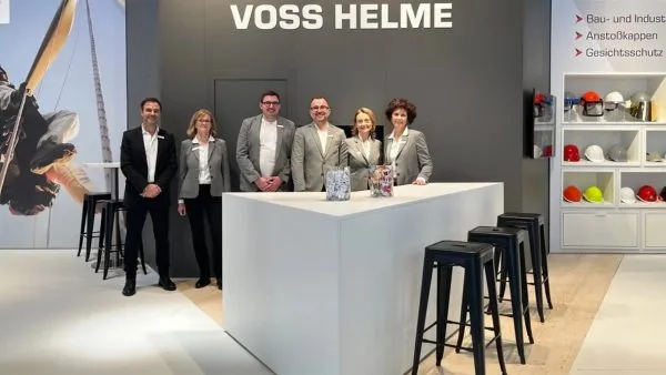 Gruppe von Personen bei einer Feierstunde an einem Tisch mit Pokal
