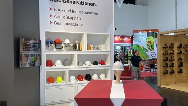 Regal mit Schutzhelmen und Zubehör am Voss-Helme-Messestand, A+A 2025 Düsseldorf