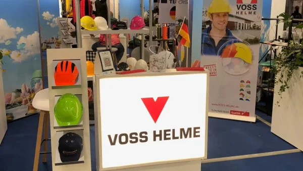 Frau am Messestand von Voss Helme auf der PSI-Messe mit ausgestellten Werbeartikeln